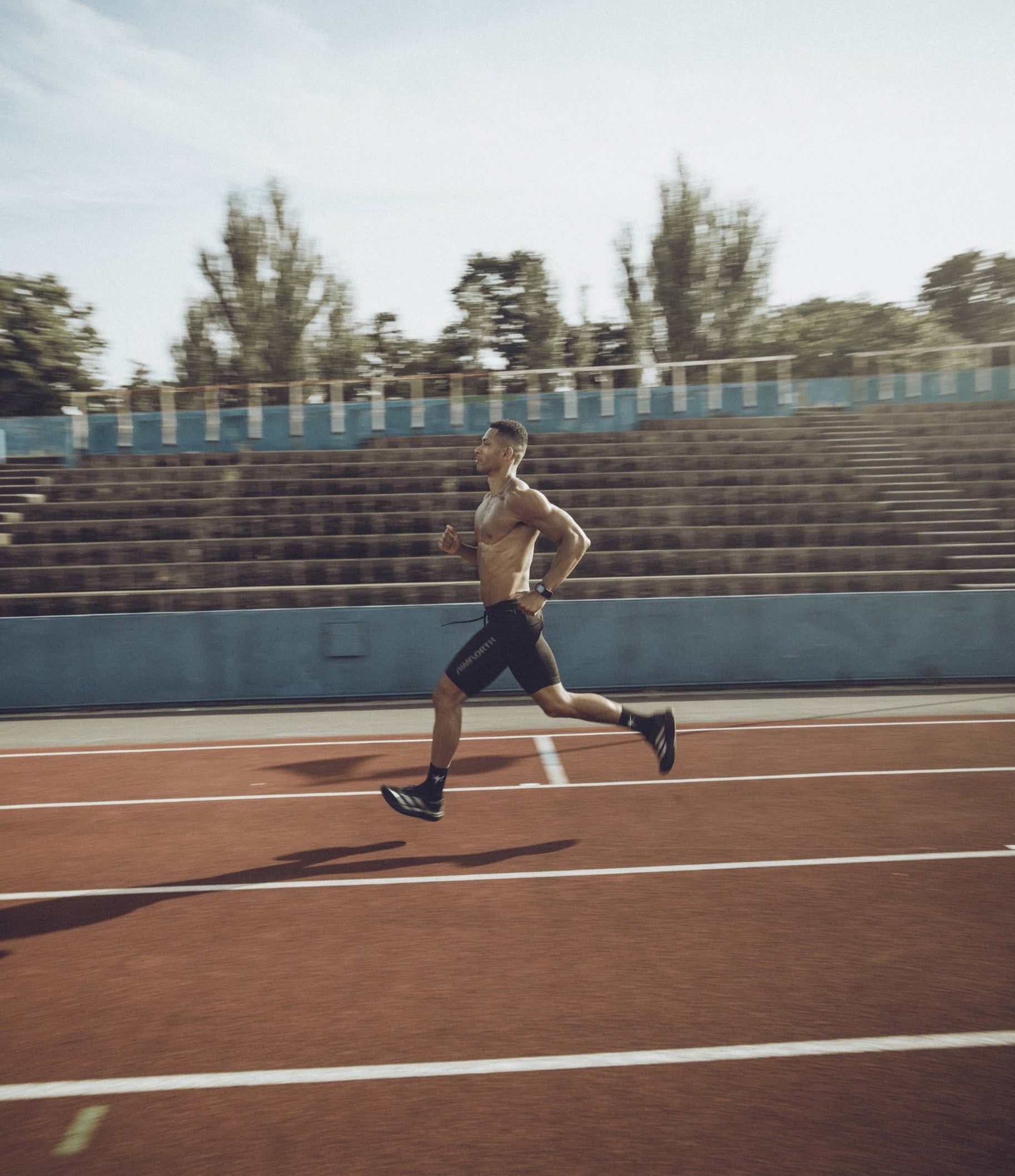 Man running on a track with trees in the background
